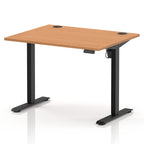 An adjustable standing desk with a light brown wood-grain desktop and black metal legs, shown on a white background with a subtle reflection.