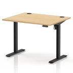 An adjustable standing desk with a light natural wood grain top and black metal legs, shown on a clean white background.