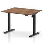 An adjustable standing desk with a medium brown wood-grain desktop and black metal legs, shown on a clean white background.