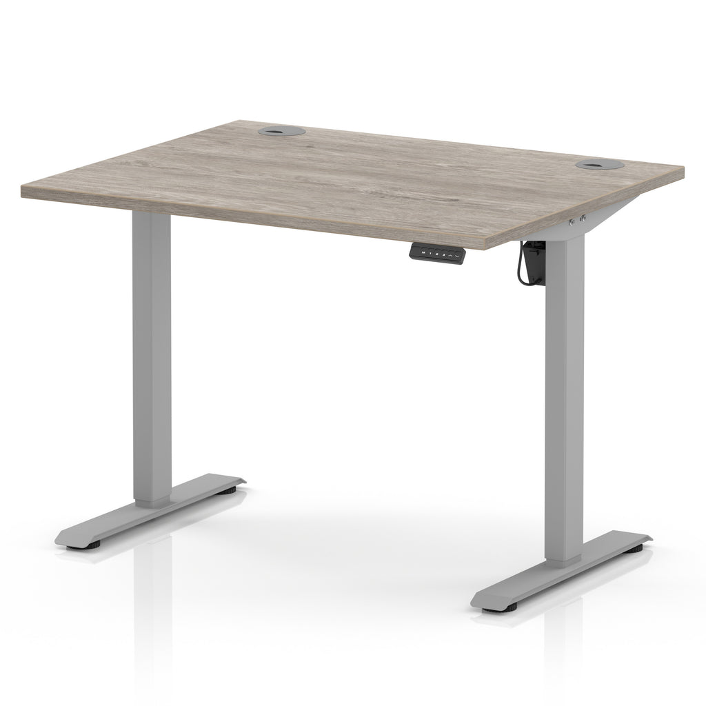 An adjustable height standing desk with a light grey wood-grain top and a silver metal frame, shown on a white background.