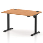 An adjustable height standing desk with a light brown wood-grain top and black metal legs, shown on a white background.