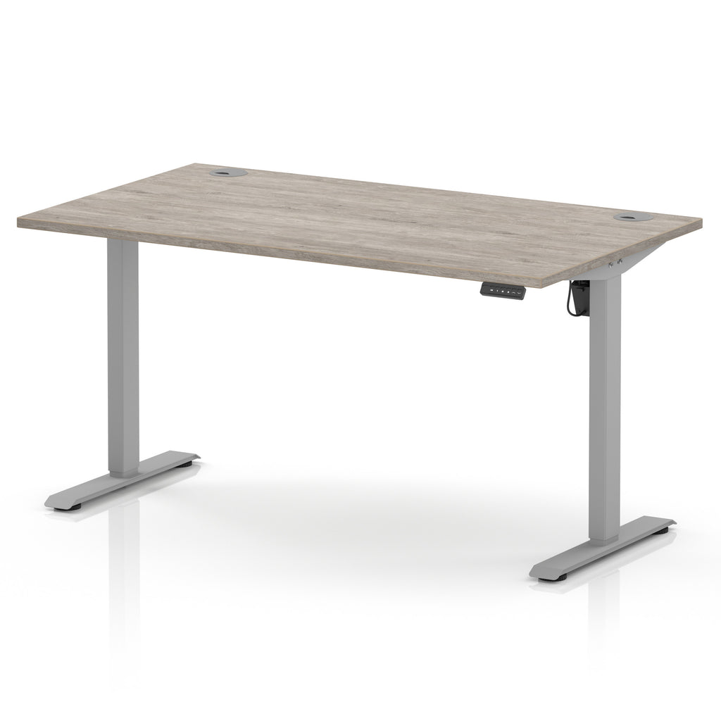 An adjustable height standing desk with a light grey wood-grain desktop and a silver metal frame with T-style legs, shown on a white background.