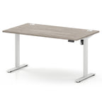An adjustable height standing desk with a light grey wood-grain top and white metal legs, shown on a clean white background.