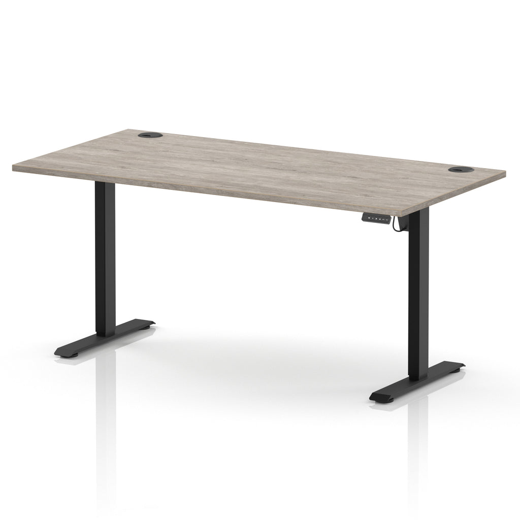 A modern height-adjustable standing desk with a light grey wood-grain desktop and black metal legs, shown on a clean white background.