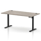 A modern height-adjustable standing desk with a light grey wood-grain desktop and black metal legs, shown on a clean white background.