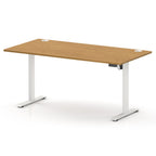 An adjustable height standing desk with a light brown wood grain top and white metal legs, shown on a clean white background.