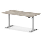 Height adjustable desk with grey wood-effect top and silver frame on a white background