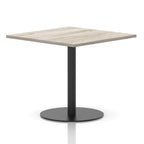 Square table with a grey wood-effect top and black cylindrical base on a white background