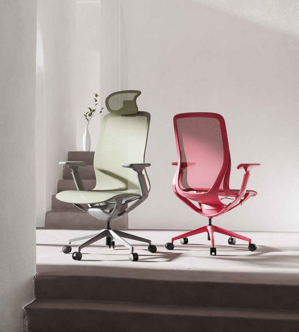 Two ergonomic mesh office chairs with adjustable armrests and five-wheel bases are displayed in a minimalist interior setting. One chair is sage green and the other is red, both on metal bases.