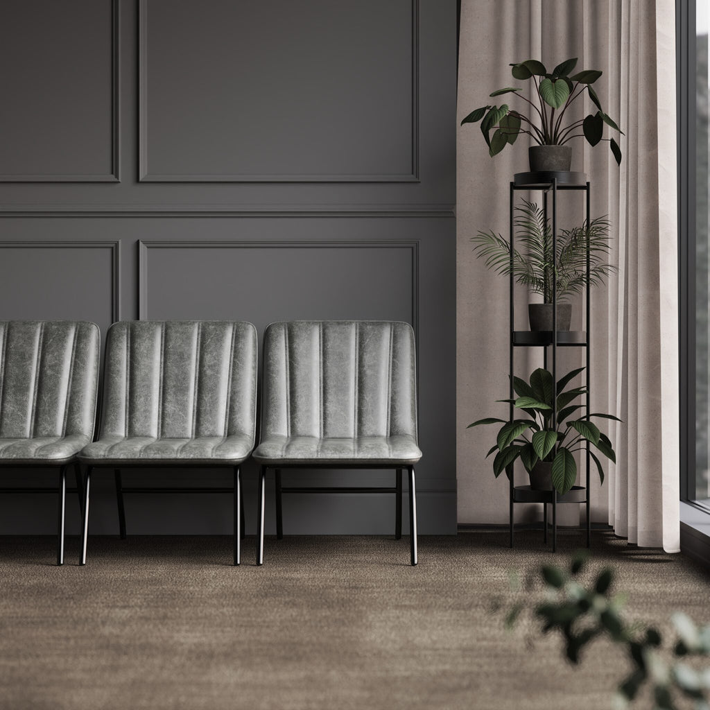 Grey upholstered bench against a dark panelled wall with a plant stand in the corner.