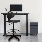 Black adjustable desk with chair and computer setup in a minimalistic room.