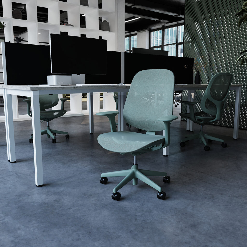 A blue ergonomic office chair with a mesh back and five-star wheeled base, positioned in front of a desk with multiple computer monitors in a modern office setting.
