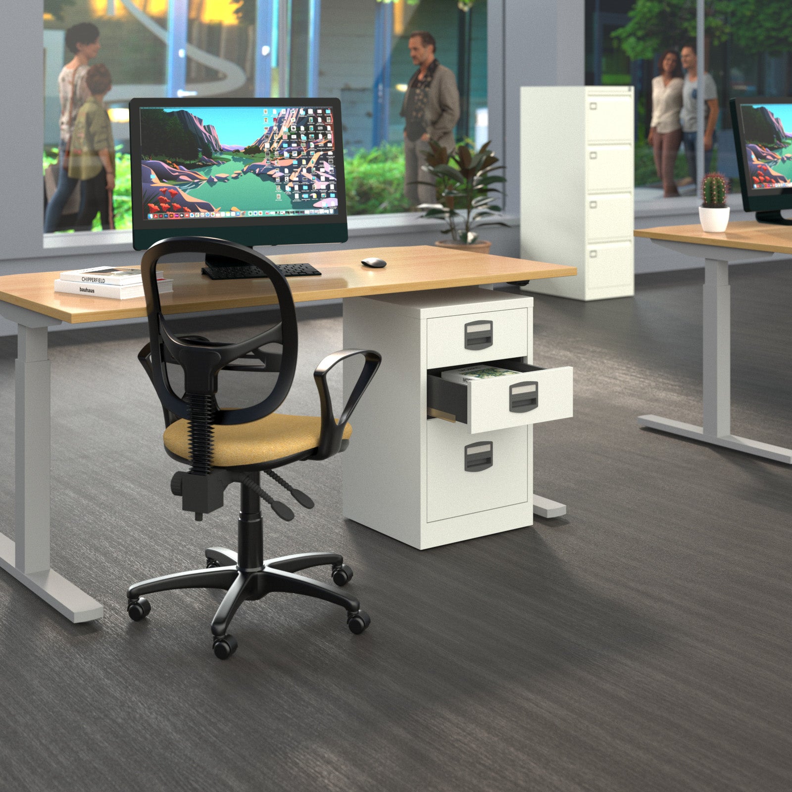 A modern office setup featuring a white three-drawer pedestal file cabinet with an open drawer, paired with a black mesh office chair and a light wood desk surface. The scene is set in a bright office with grey flooring, other desks, and blurred people visible in the background.