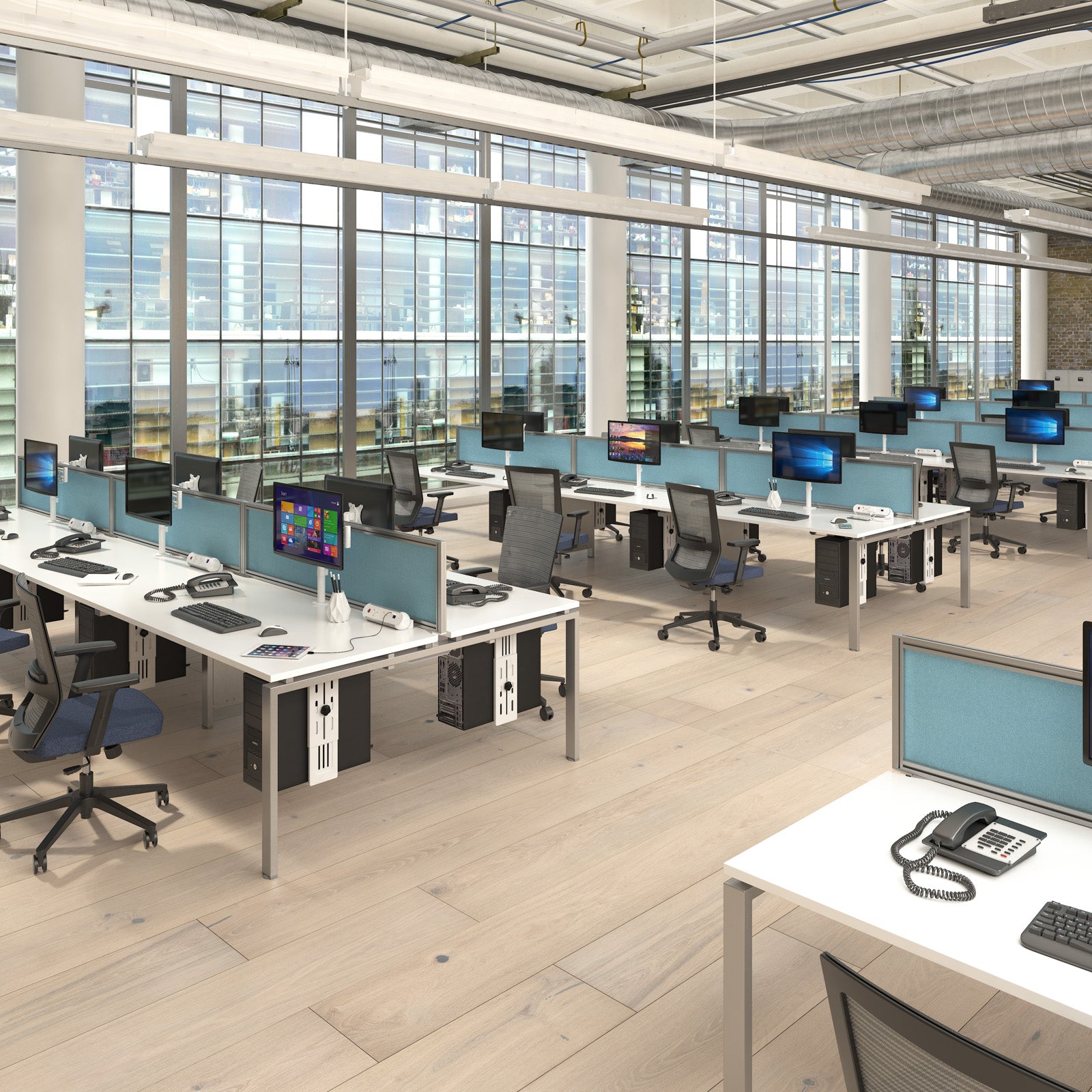 Modern office with desks, chairs, and computer monitors in a large room with large windows.