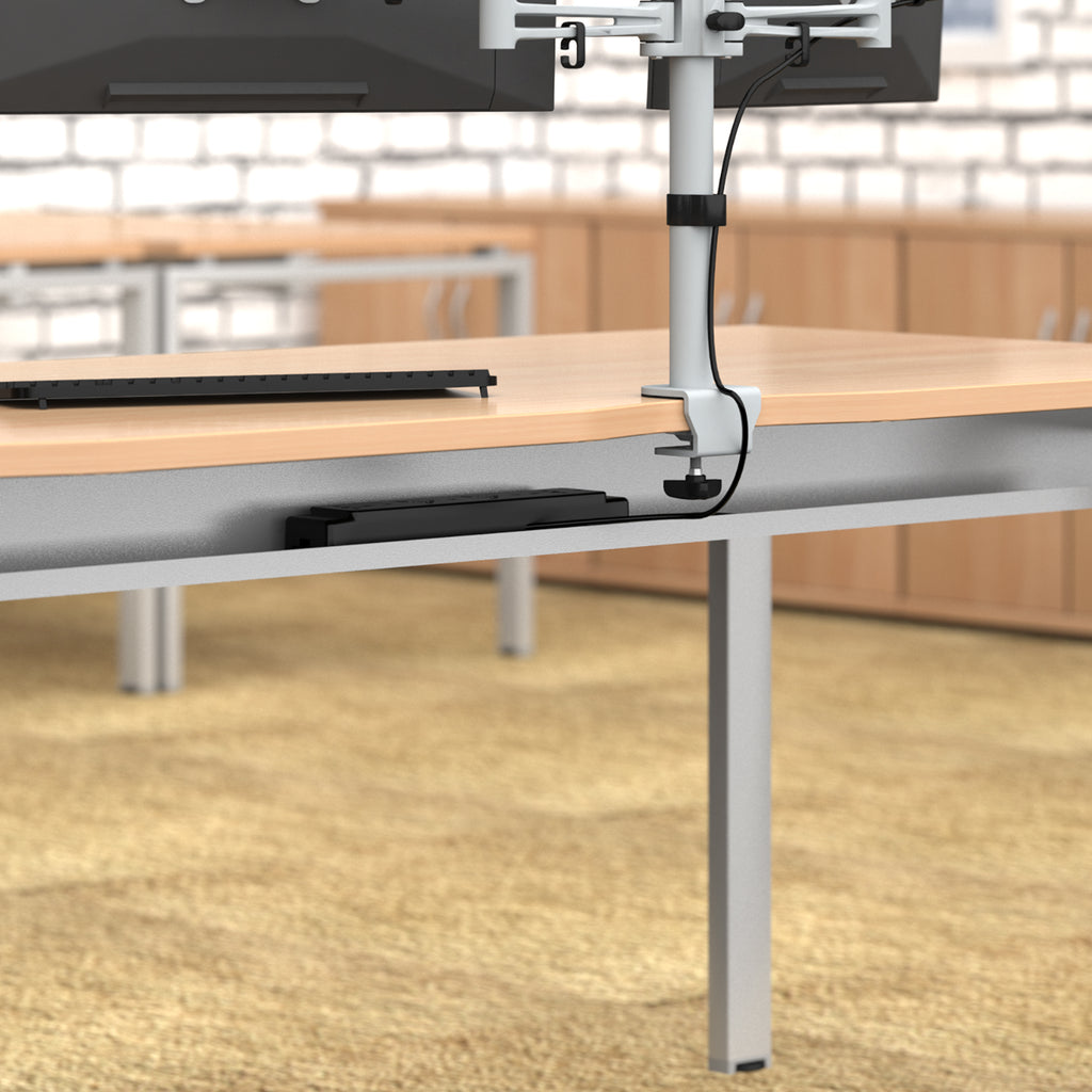 Table with a monitor stand and metal cable tray in an indoor setting