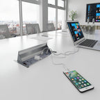 Laptop and smartphone charging on a desk with a cityscape view