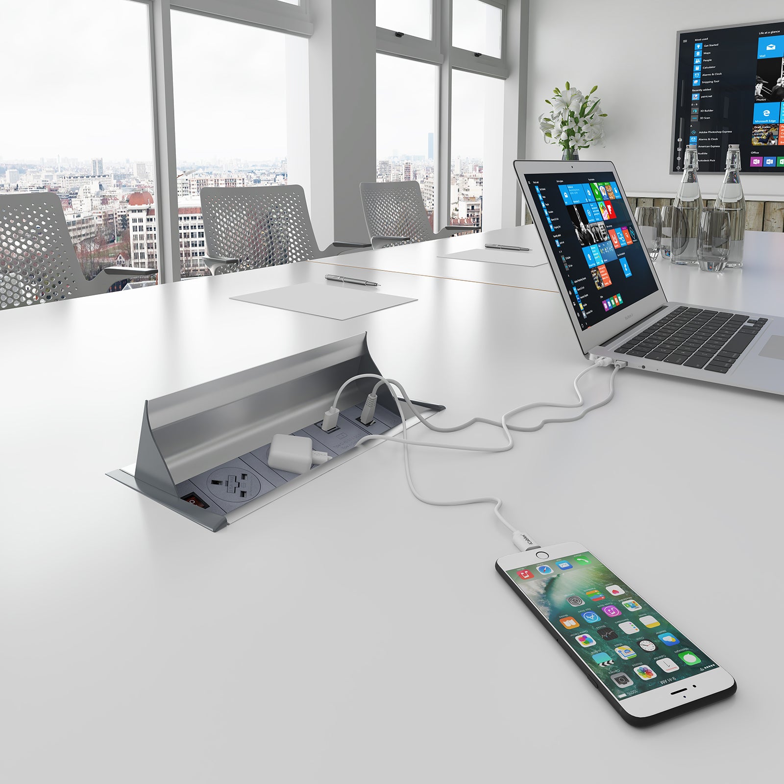 Laptop and smartphone charging on a desk with a cityscape view