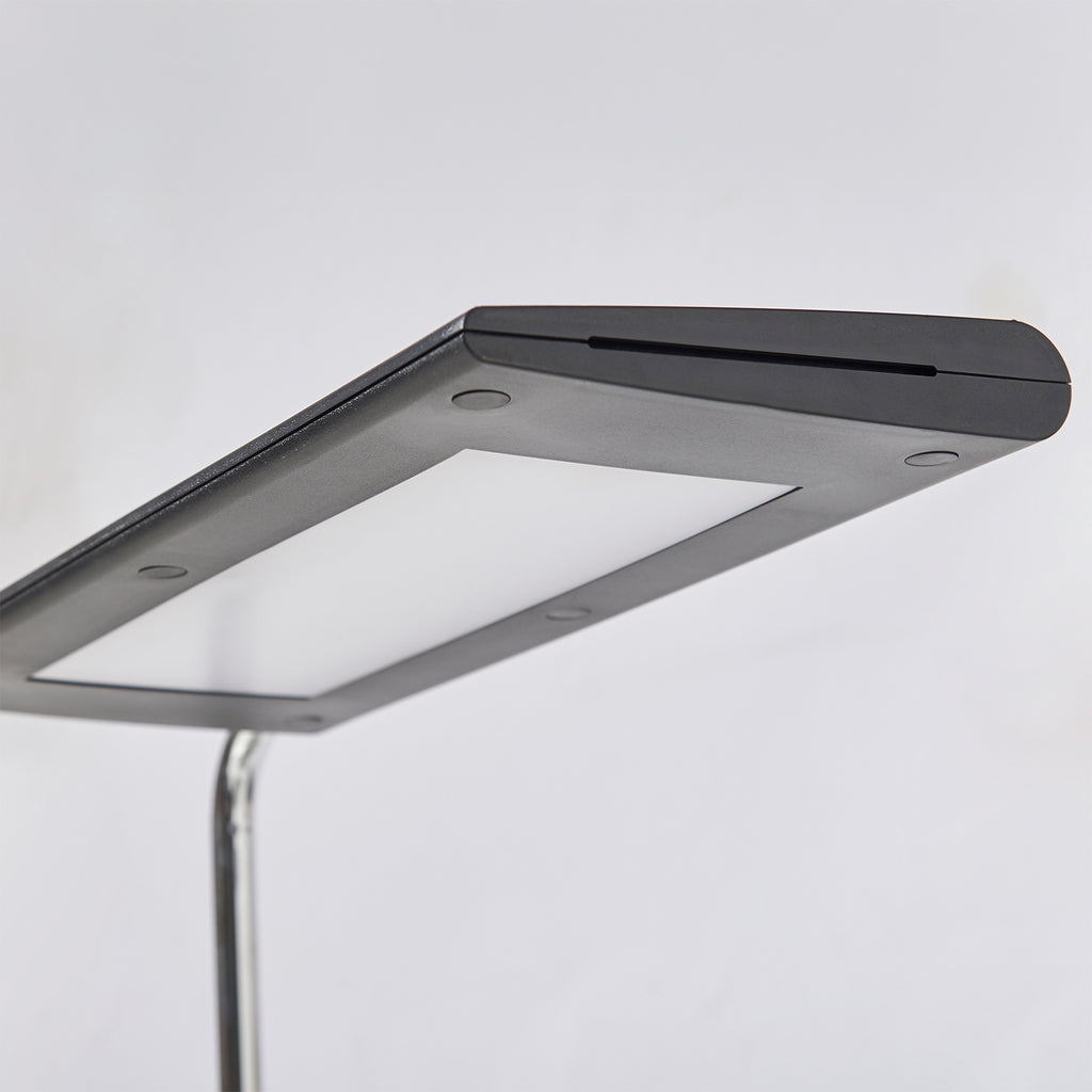 A close-up of a modern rectangular lamp with a matte black top cover, a silver metallic frame shown against a plain light grey background.