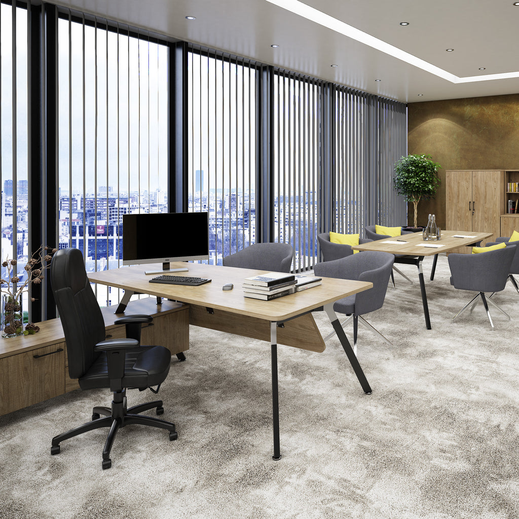 Modern office interior with a light wood desk, black office chair, computer monitor, grey chairs, and large vertical blinds over a city view.