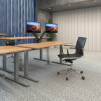 Modern office setup with desks, chairs, and monitors in a room with concrete walls.