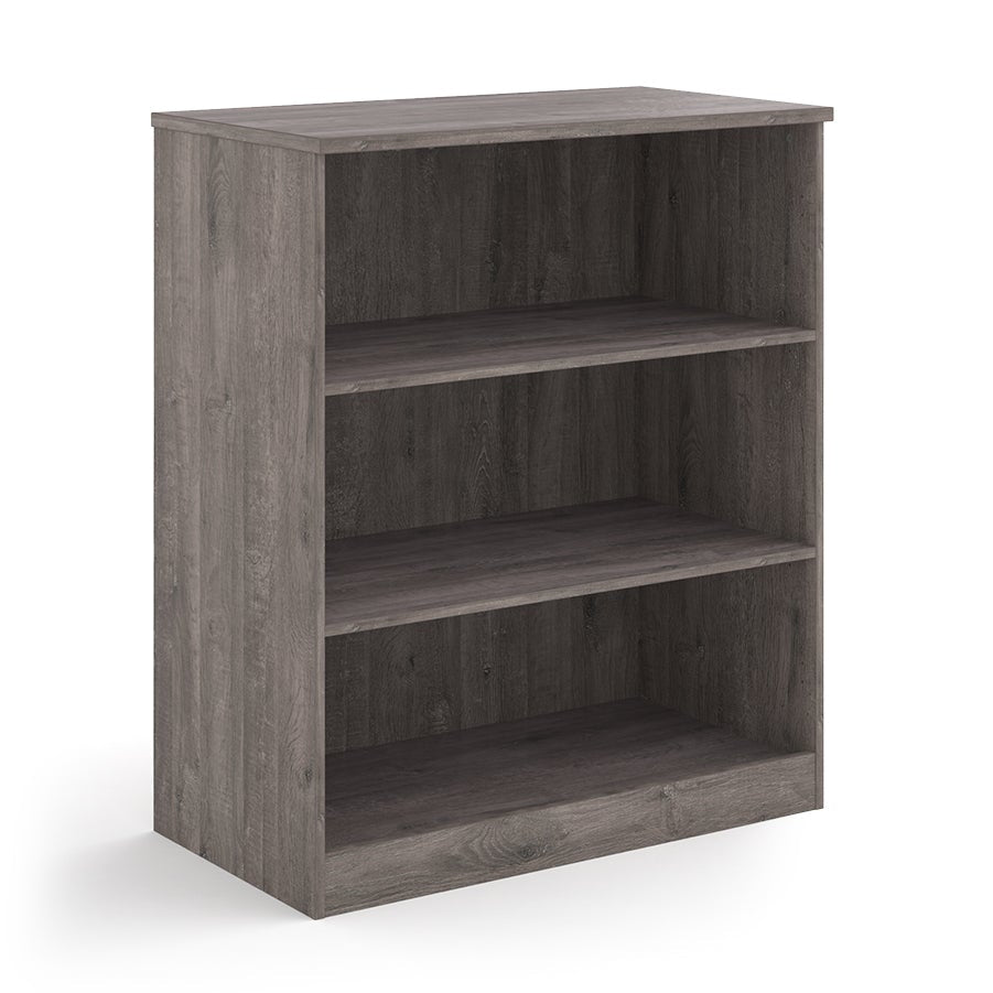 A three-tier bookcase with a grey wood-effect finish, shown from a three-quarter angle on a solid white background.