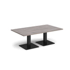 Rectangular coffee table with grey wood-effect top and two black metal square bases, shown on a white background