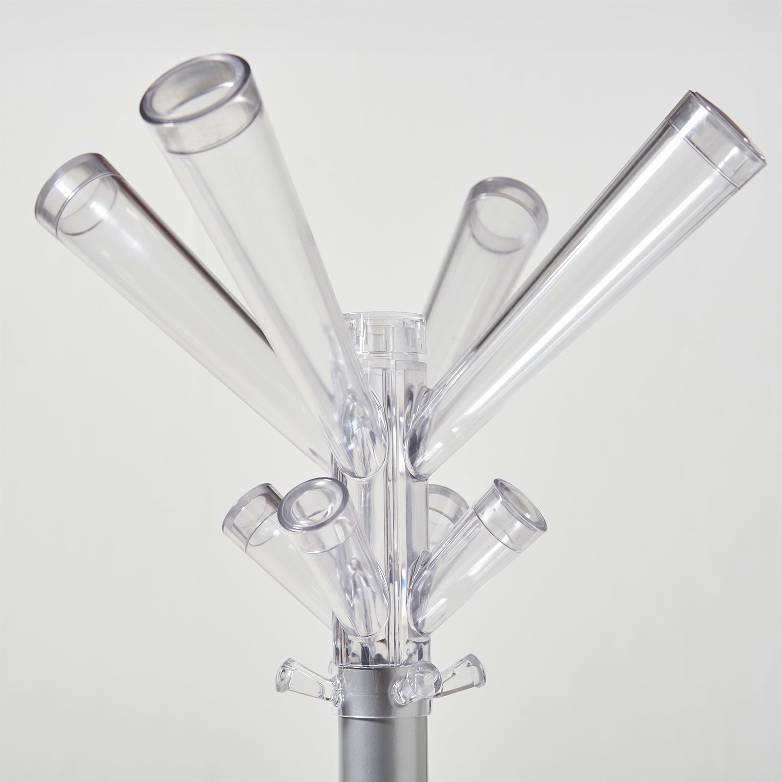 Clear acrylic coat rack with multiple angled cylindrical hooks on a silver metal stand, photographed against a light gray background.