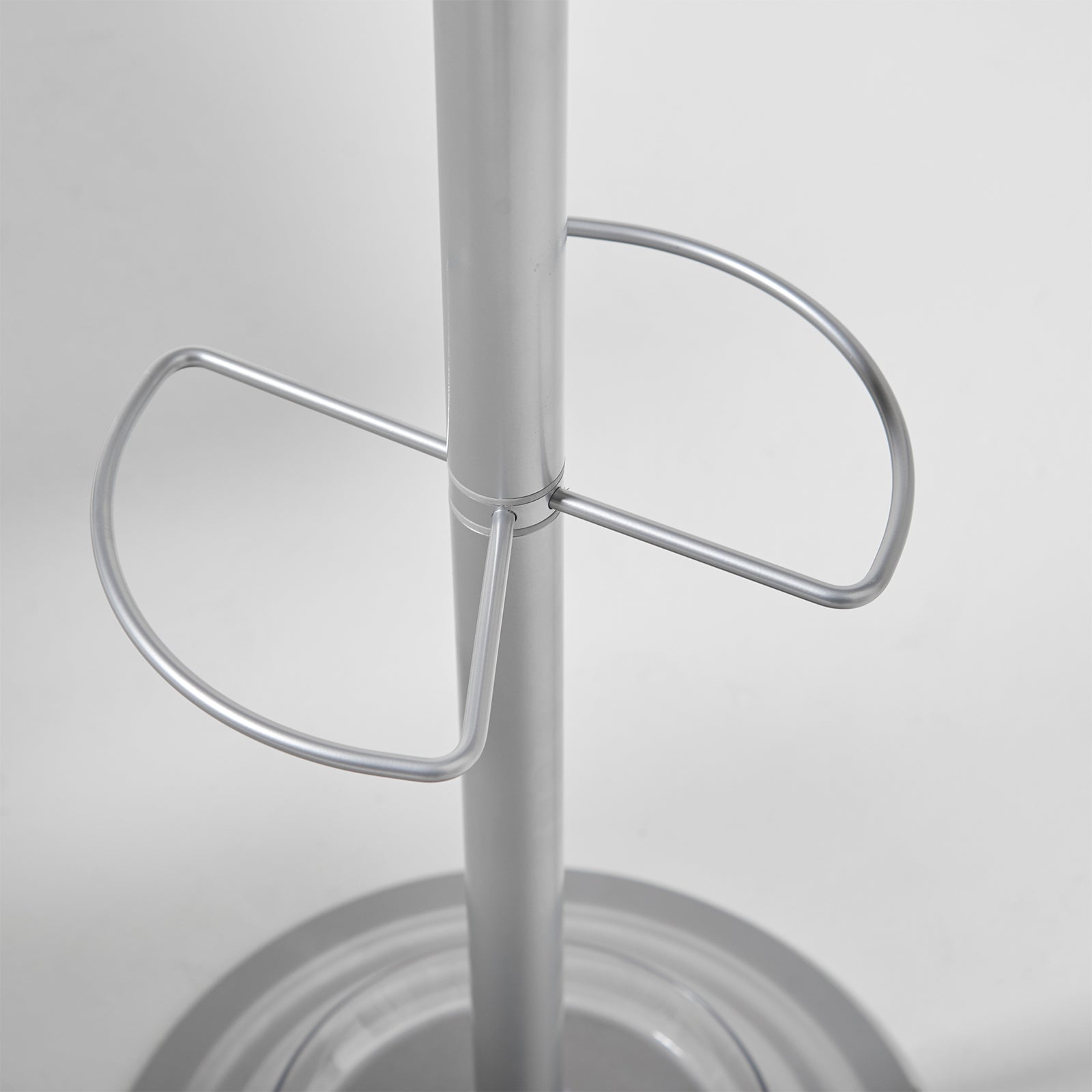 A close-up of a metallic silver metal stand with a central vertical pole and two curved support loops, set against a plain light gray background.