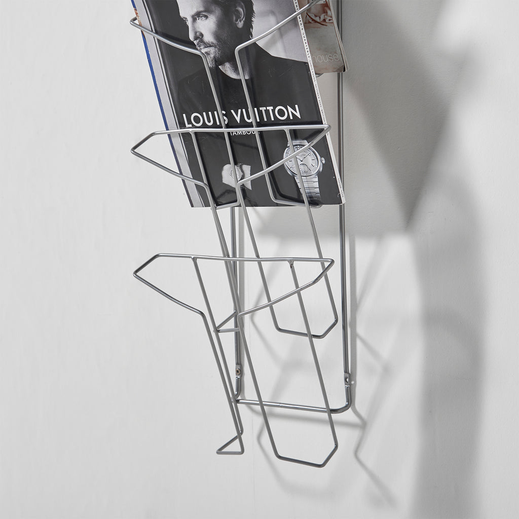 Metal wire wall display with a magazine on a grey background