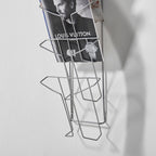 Metal wire wall display with a magazine on a grey background
