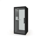 A modern black privacy booth with a glass door, featuring a built-in white shelf and a vertical black handle, shown on a plain white background.
