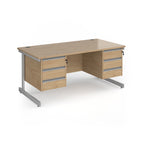 A modern office desk with a light oak wood grain finish and silver metal legs, featuring three drawers on the left and three drawers on the right.