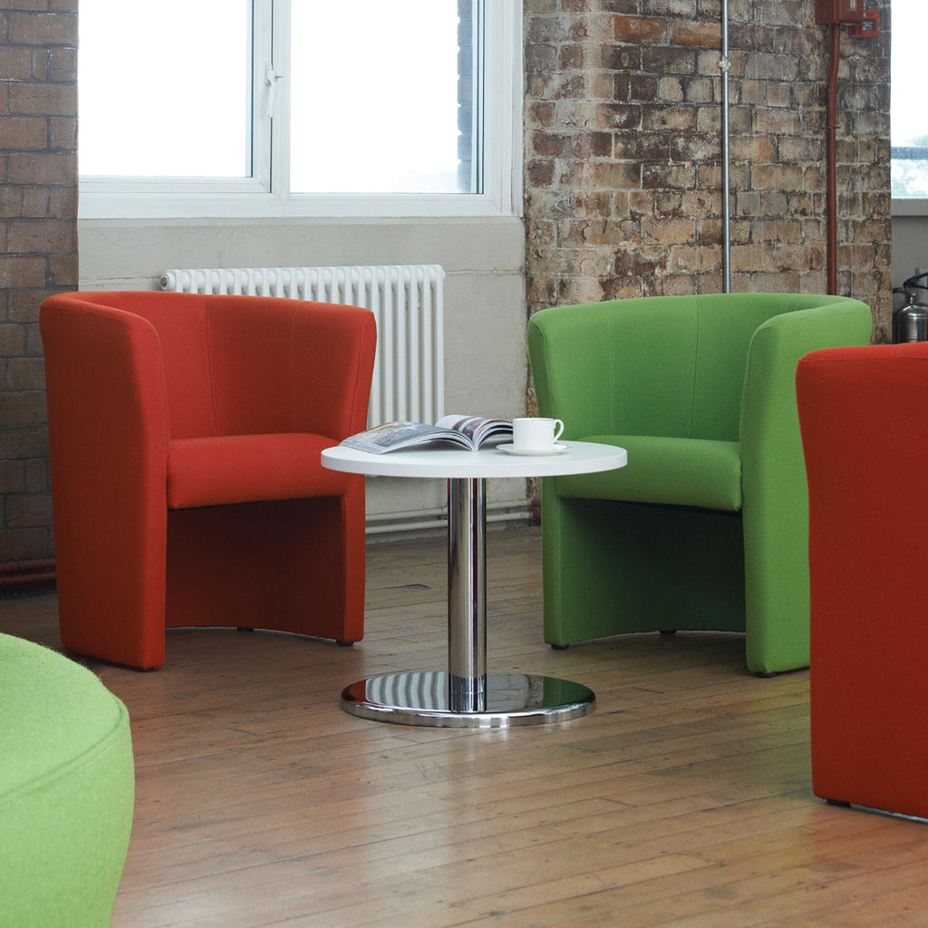 Modern interior with red and green chairs around a white table.