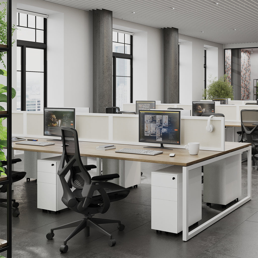 Modern office setup with desks, chairs, and computer monitors in a bright room.