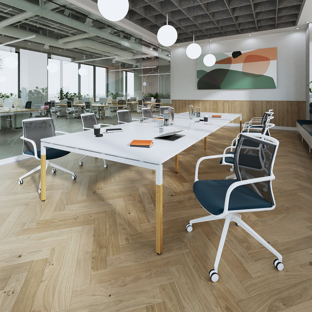 Modern office space with a long white table and chairs on a wooden floor.