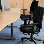 Office setup with a round wooden table and black office chairs.