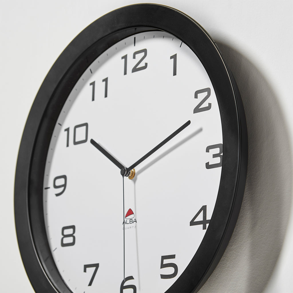 Wall clock with black frame and white face on a light grey background