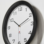 Wall clock with black frame and white face on a light grey background