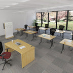 A modern classroom or office space with multiple light wood desks, black mesh office chairs, a whiteboard, and large windows overlooking a landscaped outdoor area.