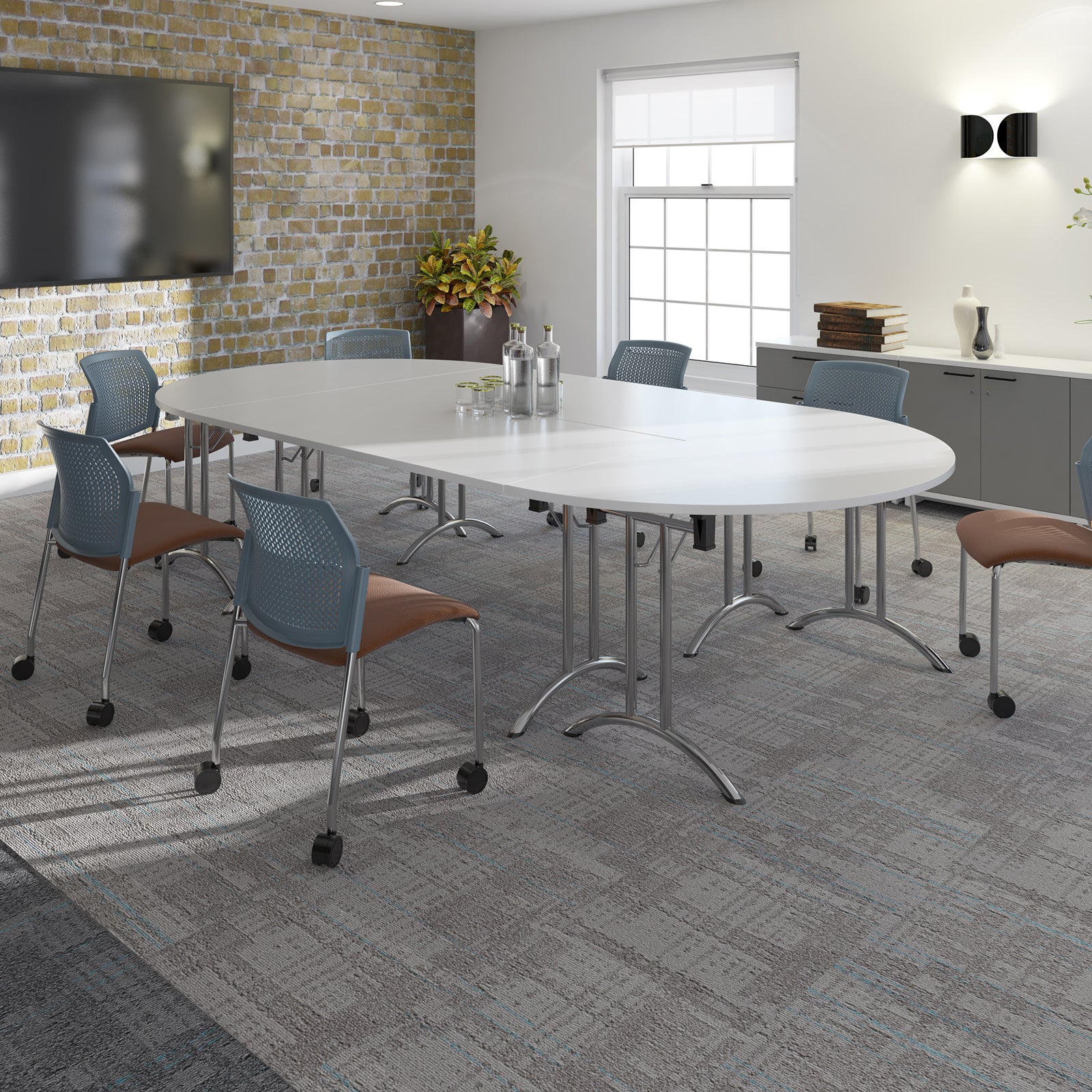 A modern conference room setup featuring a large oval white meeting table with chrome legs, surrounded by blue mesh swivel chairs with brown upholstered seats, set on a grey patterned carpet.