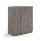 A two-door cabinet with a grey wood grain finish, featuring two vertical doors with slim silver handles and small lock keys, shown on a plain white background.