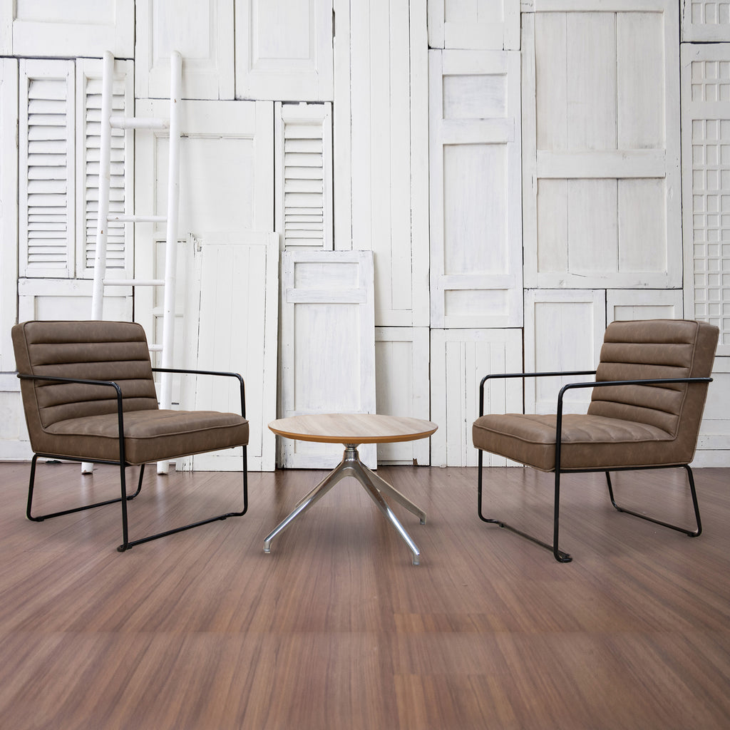 Two brown chairs with black frames and a small round table in a room with white paneled walls.