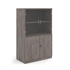 A grey wood grain office bookcase with two lower cabinet doors, one open upper shelf, and two small wall-mount hooks on the back panel, shown on a white background.