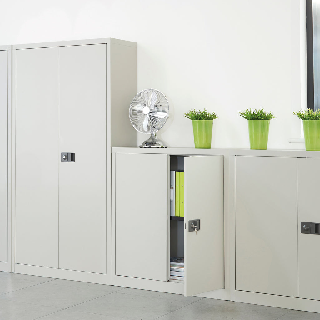 White storage cabinets with a fan and green plants on a white background
