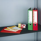 Colorful binders and office supplies on a shelf against a gray wall.