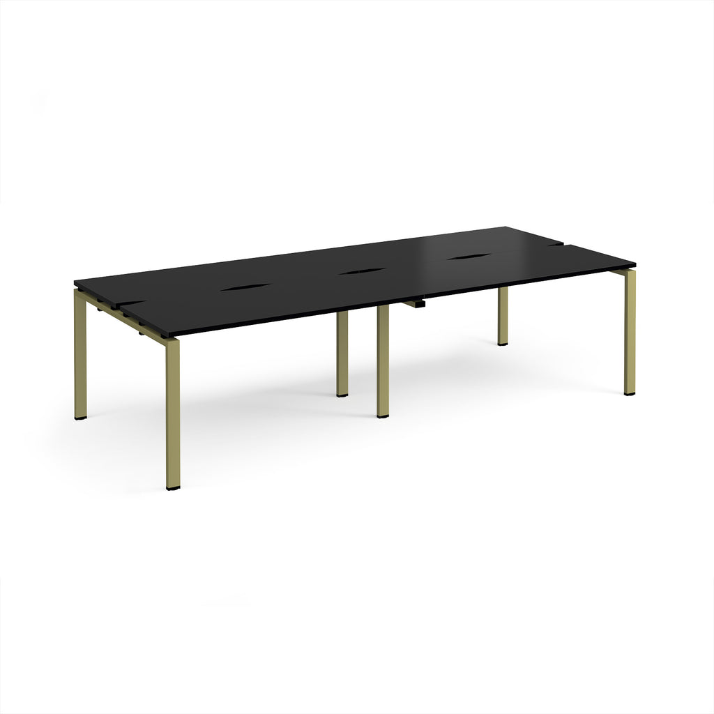Four back-to-back desks with black tops and green metal frame on a white background