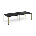 Four back-to-back desks with black tops and green metal frame on a white background