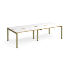 Four back-to-back desks with white tops with wooden edges and green metal frame on a white background