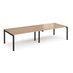 Four back-to-back desks with wood-effect tops and black metal frame on a white background