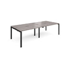 Four back-to-back desks with grey wood-effect tops and black metal frame on a white background